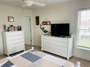 a bedroom with a tv and a white dresser at Compass Rose in Holden Beach +59 photos