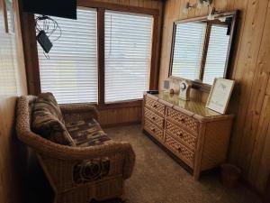 a living room with a wicker chair and a dresser at Hidden Treasure in Holden Beach