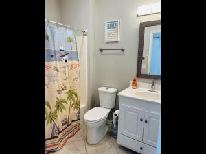 a bathroom with a toilet and a sink and a shower curtain at Avalon East-Duplex in Holden Beach
