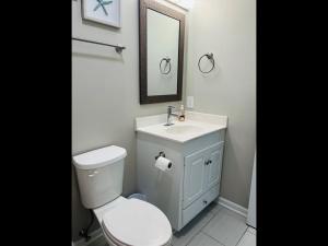 a bathroom with a toilet and a sink and a mirror at Avalon East-Duplex in Holden Beach