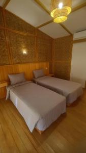 a bedroom with two beds and a chandelier at Morgans Bungalows in Maluk +7 photos
