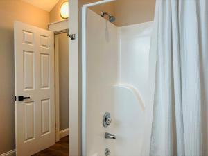 a bathroom with a shower with a white shower curtain at Nauti Time home in Holden Beach