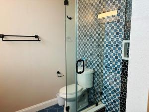 a bathroom with a toilet and a glass shower at Nauti Time home in Holden Beach