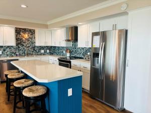 a kitchen with a stainless steel refrigerator and stools at Nauti Time home in Holden Beach