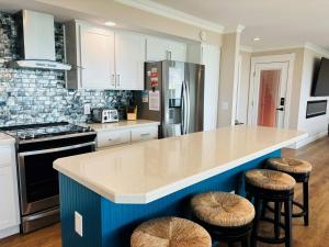 a kitchen with a blue island with stools in it at Nauti Time home in Holden Beach +46 photos