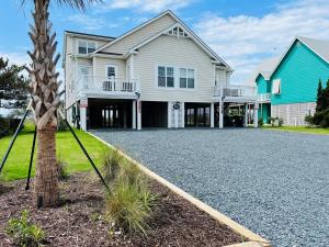 a house with a palm tree in front of it at Avalon West-Duplex in Holden Beach