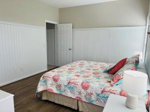 a bedroom with a bed with a floral bedspread at Avalon West-Duplex in Holden Beach