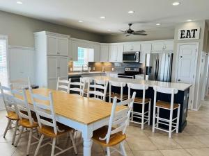 a kitchen with a wooden table and chairs and a kitchen with a counter at Avalon West-Duplex in Holden Beach