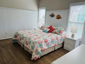 a bedroom with a bed with a floral bedspread at Avalon West-Duplex in Holden Beach