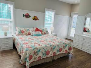 a bedroom with a bed and two dressers and windows at Avalon West-Duplex in Holden Beach +48 photos