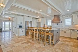 a large kitchen with white cabinets and bar stools at Cinnamon Sands home in Holden Beach