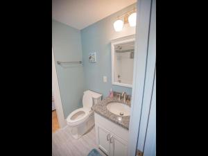 a bathroom with a toilet and a sink and a mirror at The Sandbox home in Holden Beach
