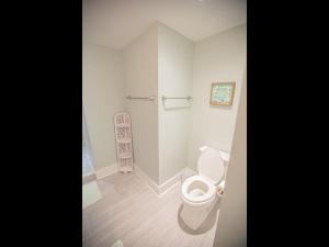 a white bathroom with a toilet and a shower at The Sandbox home in Holden Beach