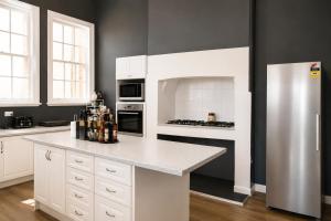 a kitchen with white cabinets and a refrigerator at Geraldton Shoreline Lodge in Geraldton +26 photos