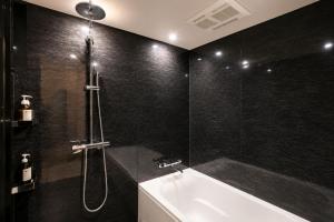 a bathroom with a shower and a tub and a sink at NAGI Hiroshima Hotel and Lounge in Hiroshima