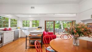a kitchen with a table and red chairs in a room at King Parrot Cottage - Close To Beach in Pearl Beach