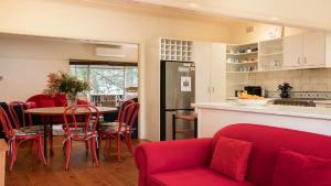 a kitchen with a red couch and a table with chairs at King Parrot Cottage - Close To Beach in Pearl Beach +16 photos