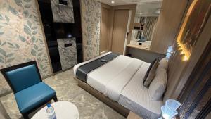 a small bedroom with a bed and a blue chair at Hotel Shree Krishna Paradise Dombivali in Dombivli