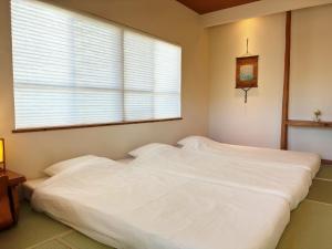 a white bed in a bedroom with a window at Guest House Ishigaki in Ishigaki Island