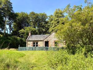 an old stone house in the middle of a field at Gunroom Cottage in Strathpeffer
