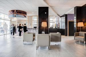 un hall avec des chaises et des personnes se déplaçant dans un bâtiment dans l'établissement Hotel ParkSaône, à Lyon