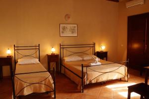 two beds in a room with two lights on the wall at Villa Pia Cornelia in Paceco