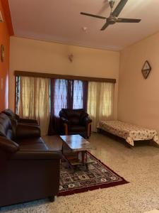 a living room with two chairs and a couch and a table at Oakville in Mysore