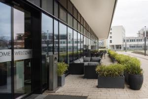 a glass building with couches and potted plants outside at INNSiDE by Meliá Wolfsburg in Wolfsburg