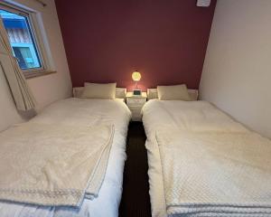 two twin beds in a small room with a lamp at Ehana Cofee Roastery Hanare in Kami-furano
