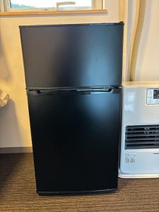 a black refrigerator sitting next to a microwave at Ehana Cofee Roastery Hanare in Kami-furano