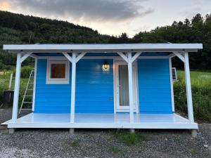 a blue tiny house with a porch and a ladder at Ehana Cofee Roastery Hanare in Kami-furano