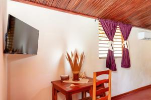 a room with a table and a tv on a wall at Blue Sky Resort in Nosy Be