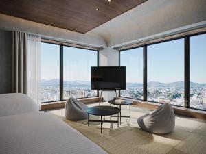 a bedroom with a bed with a television and large windows at FAV LUX Asahikawa in Asahikawa +9 photos