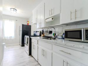 a kitchen with white cabinets and a black refrigerator at Luvienna Stays in Winnipeg