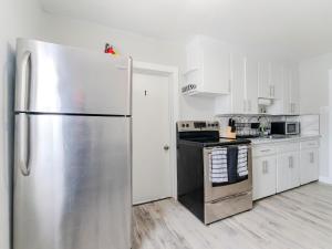 a kitchen with a stainless steel refrigerator and white cabinets at Luvienna Stays in Winnipeg +22 photos