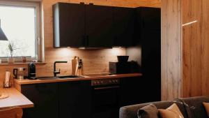a kitchen with black cabinets and a sink and a window at Sky Chalets Bühlertal in Bühlertann