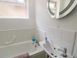 ein Badezimmer mit Badewanne, Waschbecken und Spiegel in der Unterkunft Lamora in Cheddar