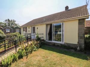 ein Haus mit Zaun und Garten in der Unterkunft Lamora in Cheddar