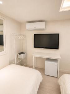 a white bedroom with a flat screen tv on the wall at Olli Haus in Seoul