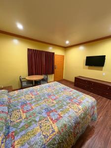 a hotel room with a bed and a flat screen tv at Sunrise Inn in South Gate
