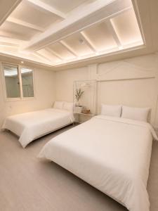 two beds in a room with white walls at Olli Haus in Seoul