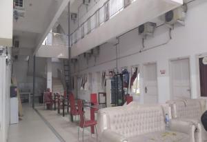 a room with white chairs and a table and a group of tables and chairs at Hotel O Wisma Fortuner in Makassar