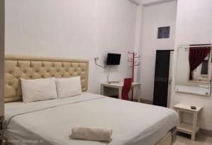 a bedroom with a large bed and a mirror at Hotel O Wisma Fortuner in Makassar