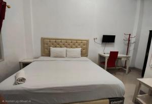 a bedroom with a large white bed and a desk at Hotel O Wisma Fortuner in Makassar