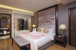 a bedroom with a large white bed with red flowers on it at Athena Hotel in Ho Chi Minh City +37 photos