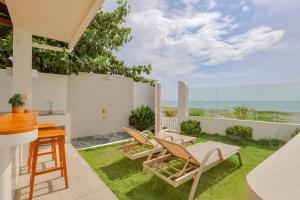 a patio with chairs and a table and a view of the ocean at Alesea Baroro, La Union, Private Modern Villa with Pool, Jacuzzi, Beachfront View in Balio