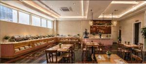 a restaurant with tables and chairs and a kitchen at Pink Suite Saigon Airport Hotel in Ho Chi Minh City