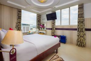 a hotel room with a large bed and windows at Pink Suite Saigon Airport Hotel in Ho Chi Minh City