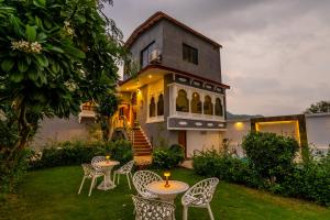 a house with tables and chairs in the yard at Next-stay in Udaipur