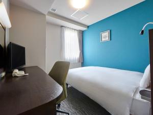 a hotel room with a bed and a desk with a computer at Comfort Hotel Sendai West in Sendai